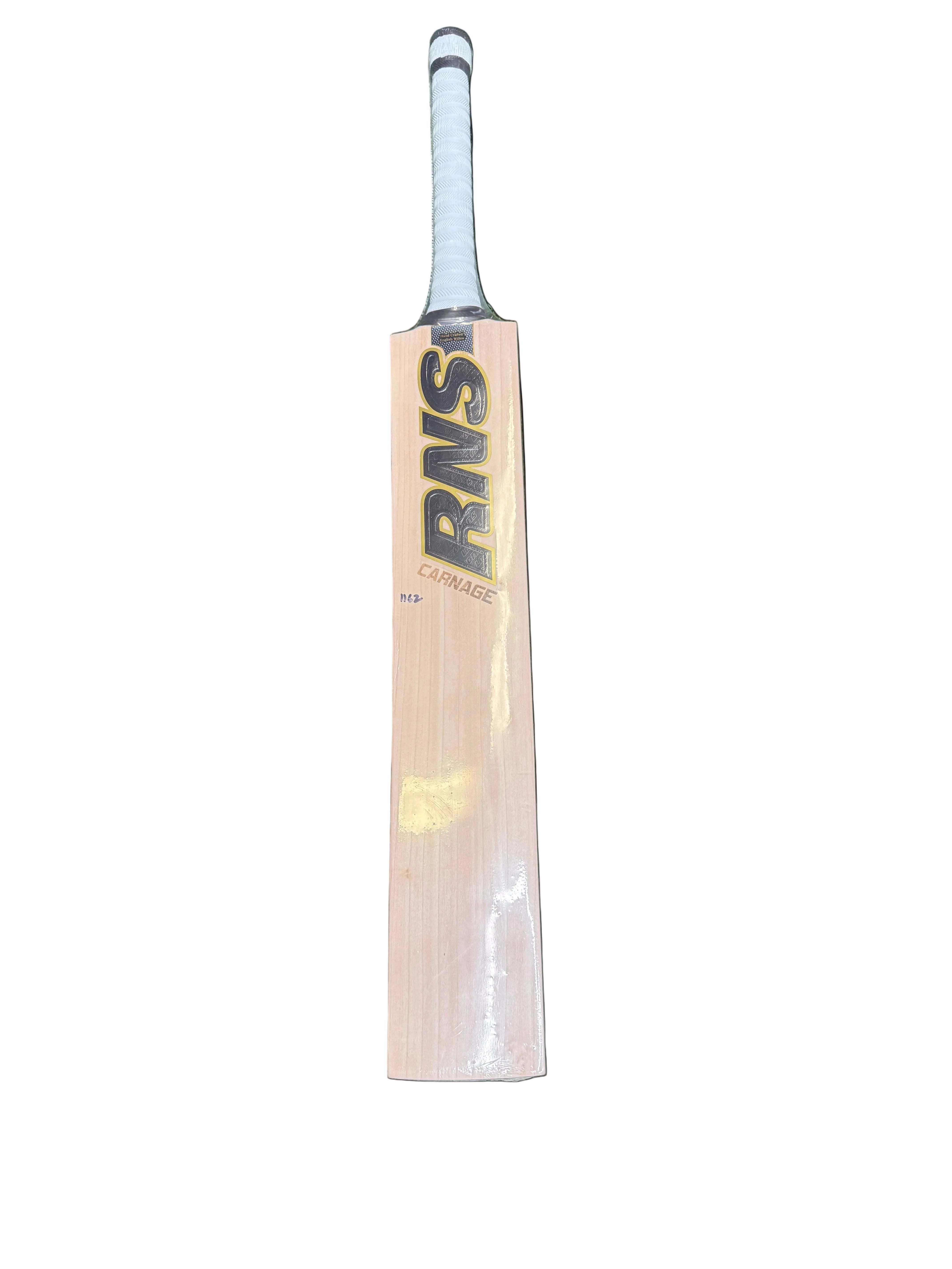 A wooden cricket bat with a light natural wood blade, black and gold RNS branding, and a white wrapped handle, lying vertically on green artificial turf.